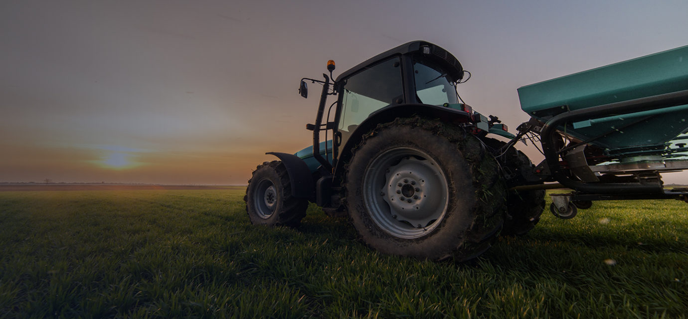 Tractor on farm land at sunrise