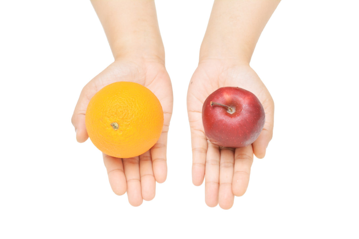an apple and an orange in a person's hands