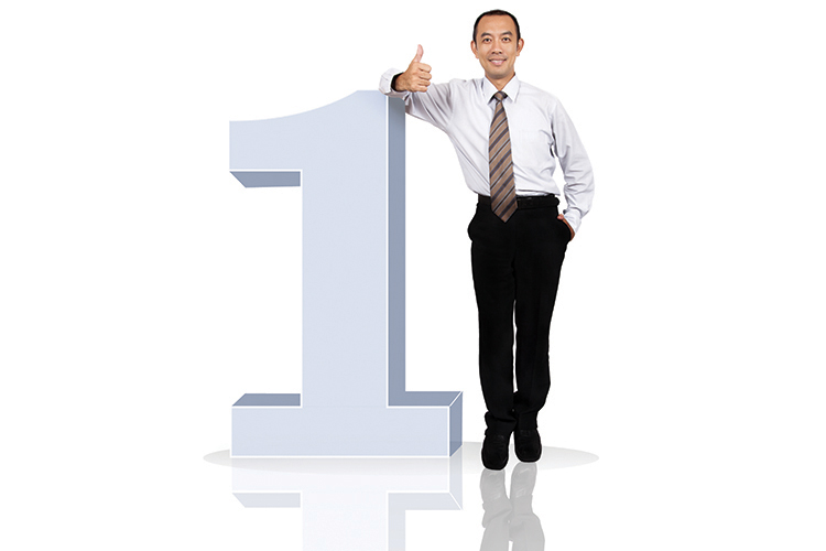 A man giving a thumbs up while leaning on a large number 1