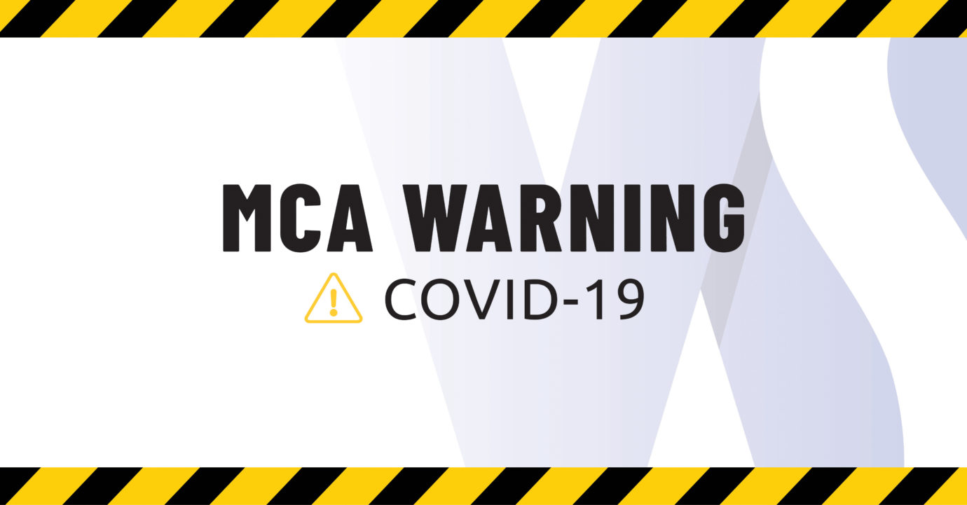 A caution sign with text that says MCA Warning Covid-19