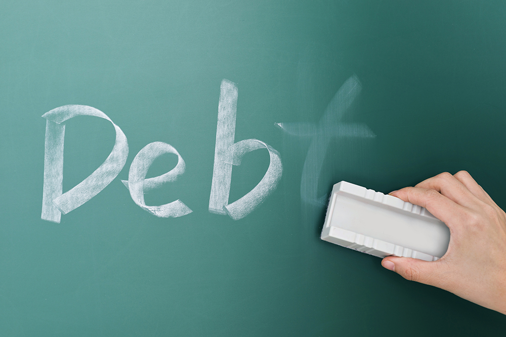 An eraser erasing the word debt written on a chalkboard, symbolizing debt relief