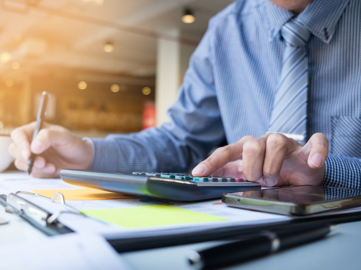 Business owner reviewing financial documents and working through numbers at a desk.